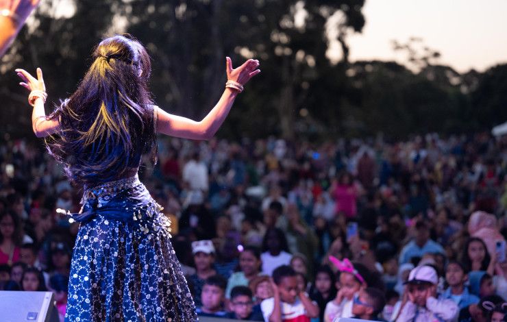 A woman dances on stage in front of a large crowd