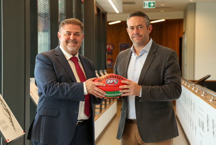 Mayor Cr Jim Memeti shaking hands with St Kilda Football Club Chief Operating Officer Simon Lethlean while holding a football