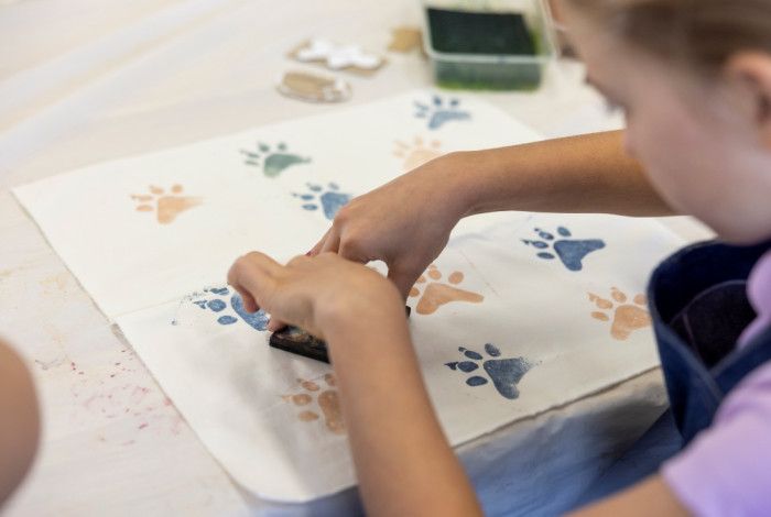  A person pressing a paw-shaped stamp onto a piece of white fabric.
