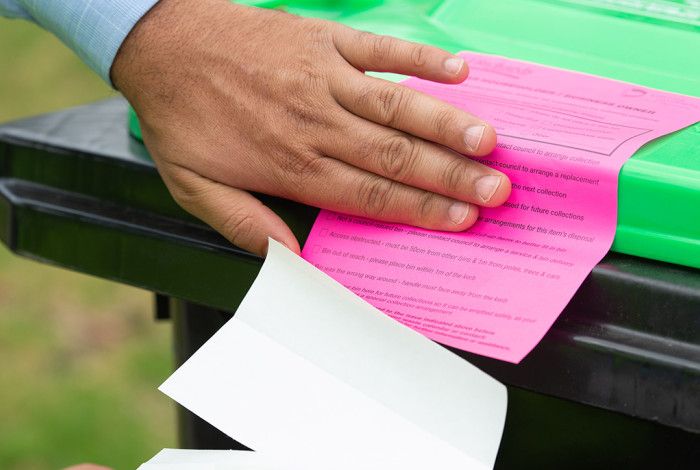 Someone putting a sticker on a bin