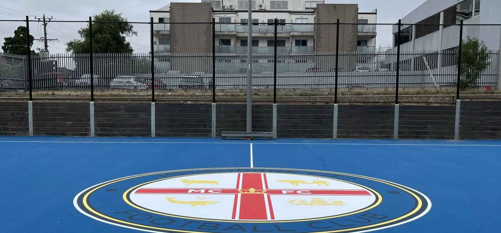 Bright blue court surface in an urban setting surrounded by high rise buildings