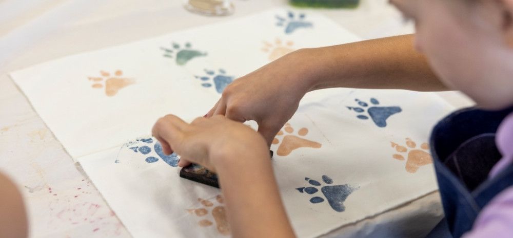  A person pressing a paw-shaped stamp onto a piece of white fabric.