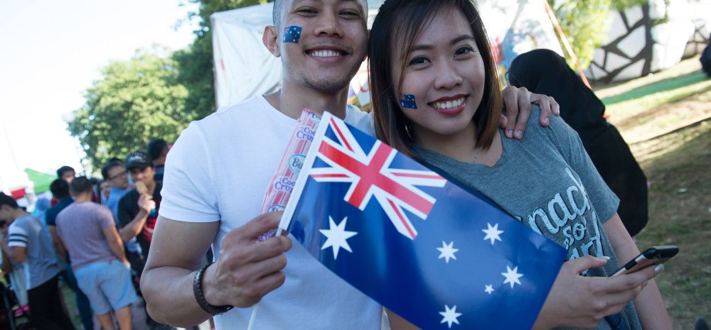 Two smiling people holding an Australian Flag