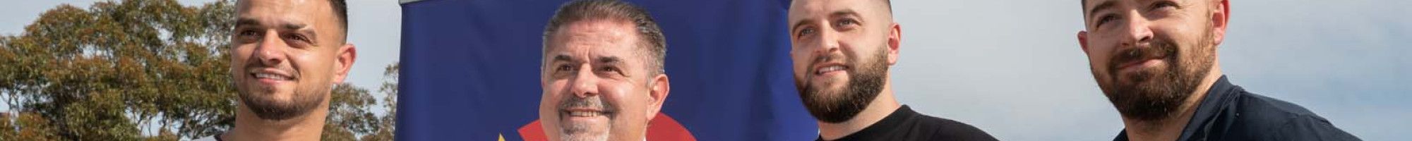 Four men standing together while one leans on a shovel.