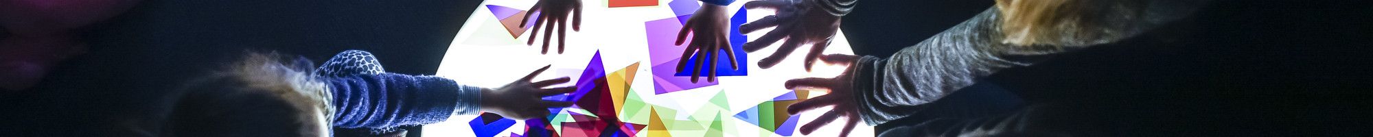 Family playing with paper shapes on light up circle.