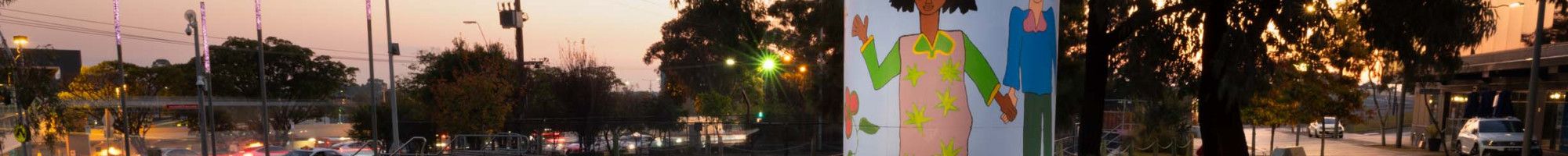 Sunset behind Settlers Square with brightly coloured art by Olana Janfa.