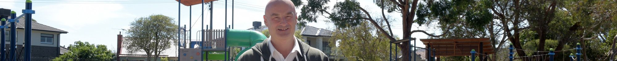 Man standing in an open gateway leading to a park