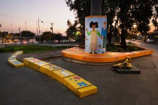 Sunset behind Settlers Square with brightly coloured art by Olana Janfa.
