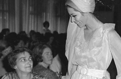 A lady looking at another lady displaying her clothes