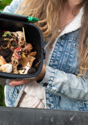 a person tipping compost into a large bin