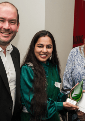 Three people with one holding an award and certificate